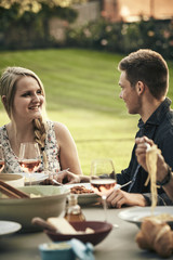 Couple eating spaghetti outdoors with friends