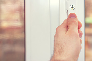 Naklejka premium The person's hand closes the window close-up.