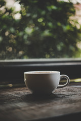 A cup of coffee on wooden table in cafe.