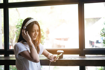 Young attractive woman listening music in headphones on windowsill background. Women lifestyle concept.