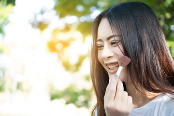 Young beautiful woman making make-up brush on her cheek. Women lifestyle concept.