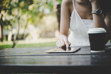 Close up of woman hands holding tablet computer on the wooden table with cup of coffee.