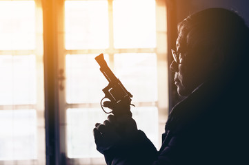 Dangerous old man pointing a gun at the target on dark background, selective focus on gun, dark tone,Crime concept
