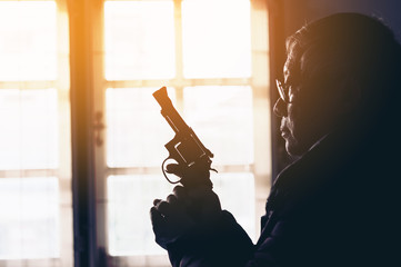 Dangerous old man pointing a gun at the target on dark background, selective focus on gun, dark...