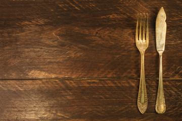 Vintage fork and knife on wooden background