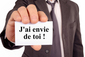Homme tenant une carte avec j'ai envie de toi écrit dessus