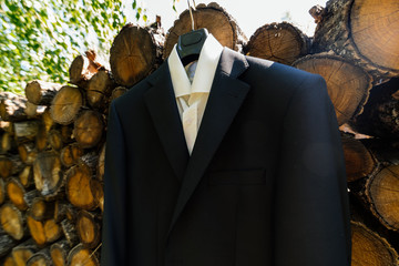 The shirt and jacket of the groom hang on a clothes hanger next to a stac