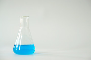 Laboratory glass Erlenmeyer conical flask filled with chemical blue liquid for a chemistry experiment in a science research lab and copy space.