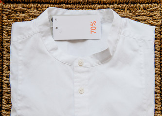 Modern fashion trendy white shirt with 70% reduction price tag on handcrafted wooden background   
