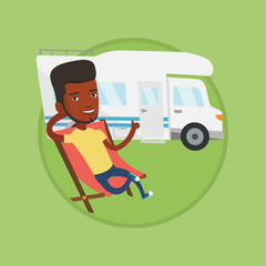 Man sitting in chair in front of camper van.