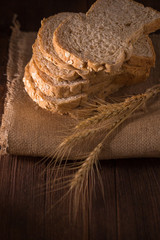 sliced whole wheat bread on wooden table, dark background.