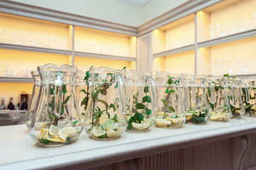 Rows of carafe of mojito-style water with lime, lemon and mint. Clean eating, diet.