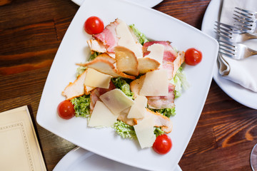 Caesar salad served on white plate in restaurant. Top view image