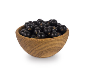 Black currant in a wooden bowl. Ripe and tasty currant isolated on white background.