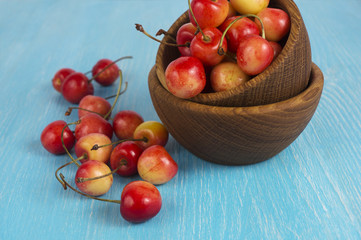 Background of ripe cherries. Pile of fresh and tasty cherries in wooden bowl. Fresh cherries scattered on a wooden table. Top view.