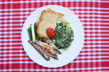 fried sprats with spinach and bread slices 