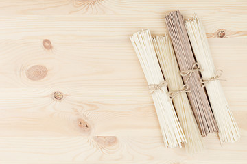 Raw asian noodles close up on beige wooden board background, top view.