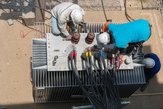 Electrician repairman worker at huge power industrial transformer installation work
