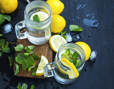 Fresh lemon infused water or soda drinks in glasses with mint, lemons and ice cubes