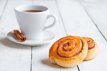 Coffee with cinnamon rolls for breakfast on white wooden table