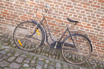 Fototapeta na wymiar Bicycle on Cobble Stone against Brick Wall
