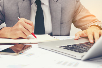 Business man working at office handing pen hand and writing message  with laptop and documents on his desk, consultant lawyer concept