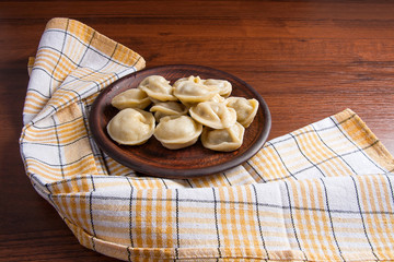 Boiled Ukrainian meat dumplings or ravioli on wooden background.