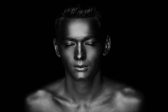 A handsome man of athletic build, completely covered in gold paint.Studio photos., Black and white