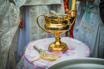 Priests standing near a container of water, praying, preparing water for sprinkling, lighting pilgrims with holy water