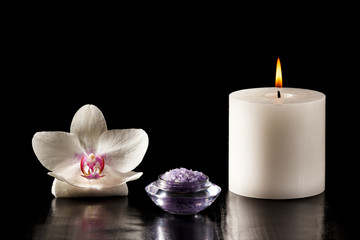 Fototapeta na wymiar White orchid flower, candle and sea salt for spa procedures on black background