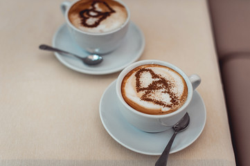 Coffee cup with milk and heart shape on a table.