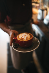 The red cup of cappuccino  in the hand 