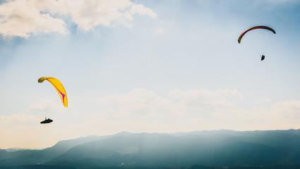 Two paragliders are flying in the valley.