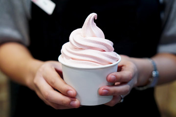 Closeup of woman 's hand holding takeaway cup with organic frozen yogurt ice cream, It's delicious...