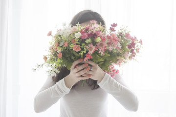 Young girl closed face with a bouquet of flowers, isolated on white background