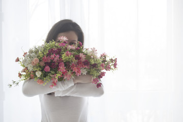 Young girl closed face with a bouquet of flowers, isolated on white, text space