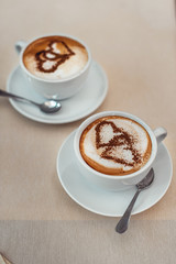 Coffee cup with milk and heart shape on a table.