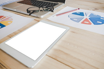 Eyeglasses on laptop keyboard with digital tablet mock up and many graph sheet  on wooden table