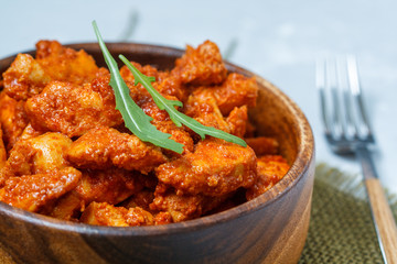 Chicken in tomato sauce in a wooden bowl.
