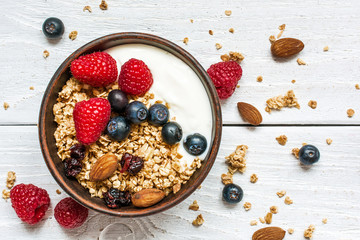 bowl of oat granola with yogurt, fresh raspberries, blueberries and nuts - obrazy, fototapety, plakaty