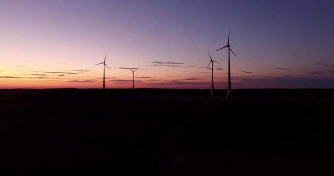 Aerial view of power generating wind turbines at the sunset