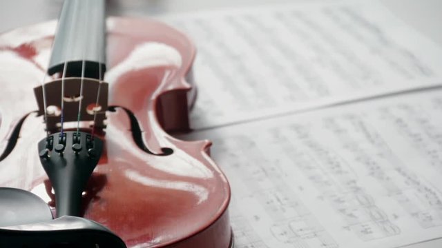 Brown violin with musical notes on a white background (spinning and panning footage). Presentation concept.