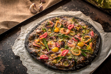 Italian pizza with black dough and seafood on a baking tray from the oven