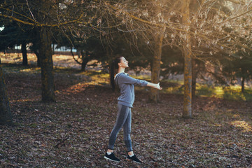 Fototapeta premium Full-height portrait sporty young woman doing stretching in park
