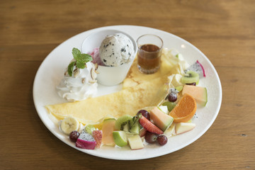 crape cake with kiwi and pineapple slices and cream on wooden board.