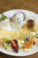 crape cake with kiwi and pineapple slices and cream on wooden board.