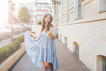 Happy woman in hat and blue dress in the city