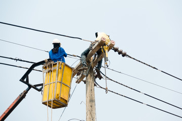 Electrical utility workers repairing problem with power line on the help of truck crane