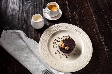 Beautiful decorated chocolate cake with golden nuts and a cup of coffee