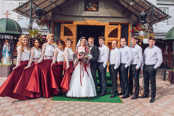 bride and groom newlyweds with happy groomsmans and bridesmaids posing at church after luxury wedding ceremony